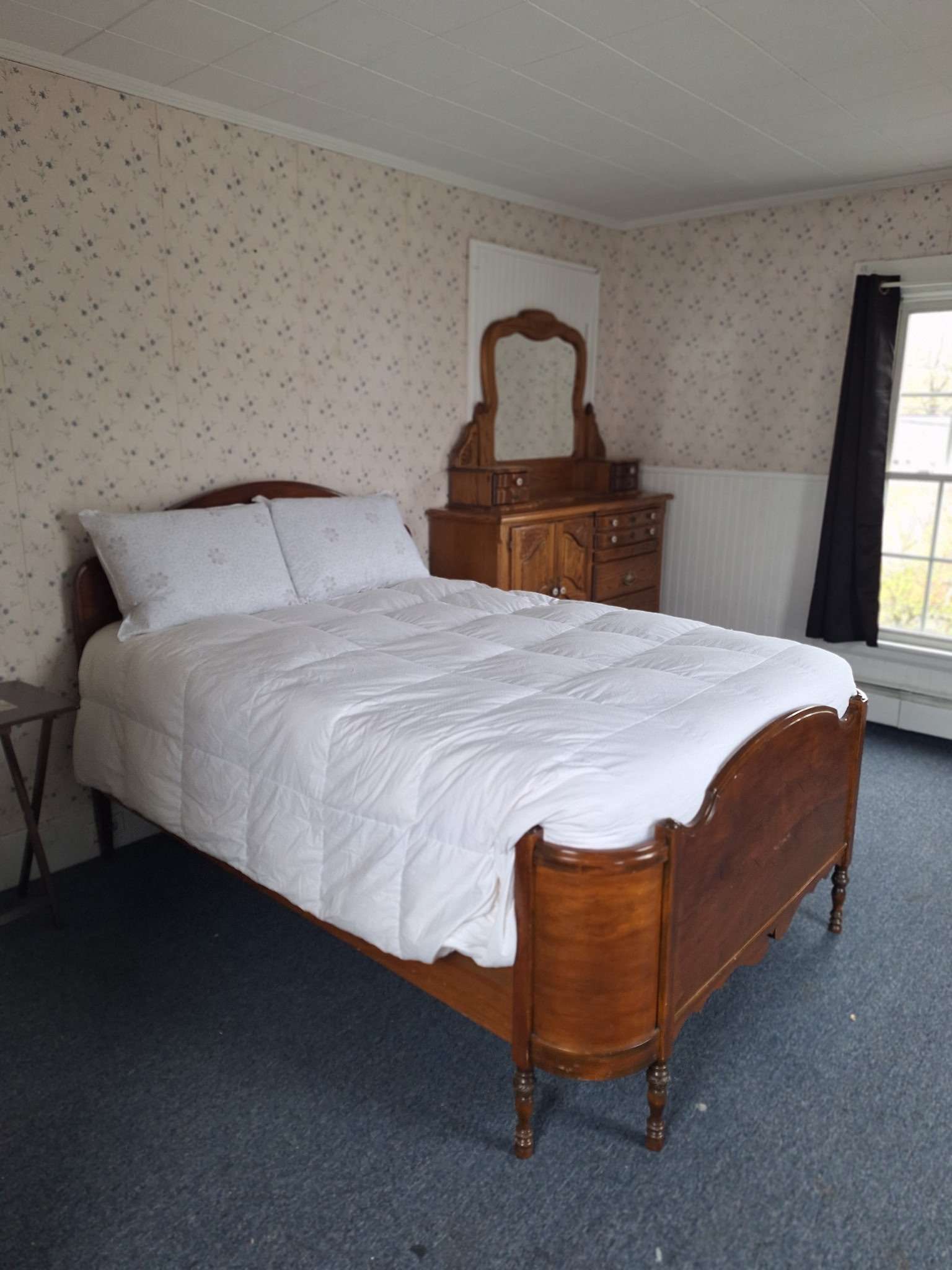 Cozy bedroom with antique wooden bed and dresser in Skowhegan contractor housing - fully furnished