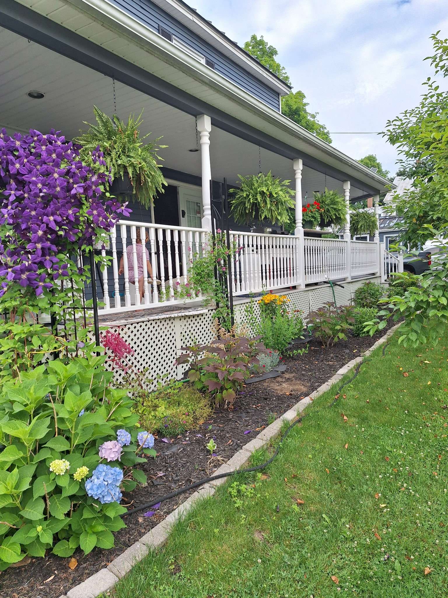 Beautiful front porch with hanging plants and flower gardens in Skowhegan contractor rental