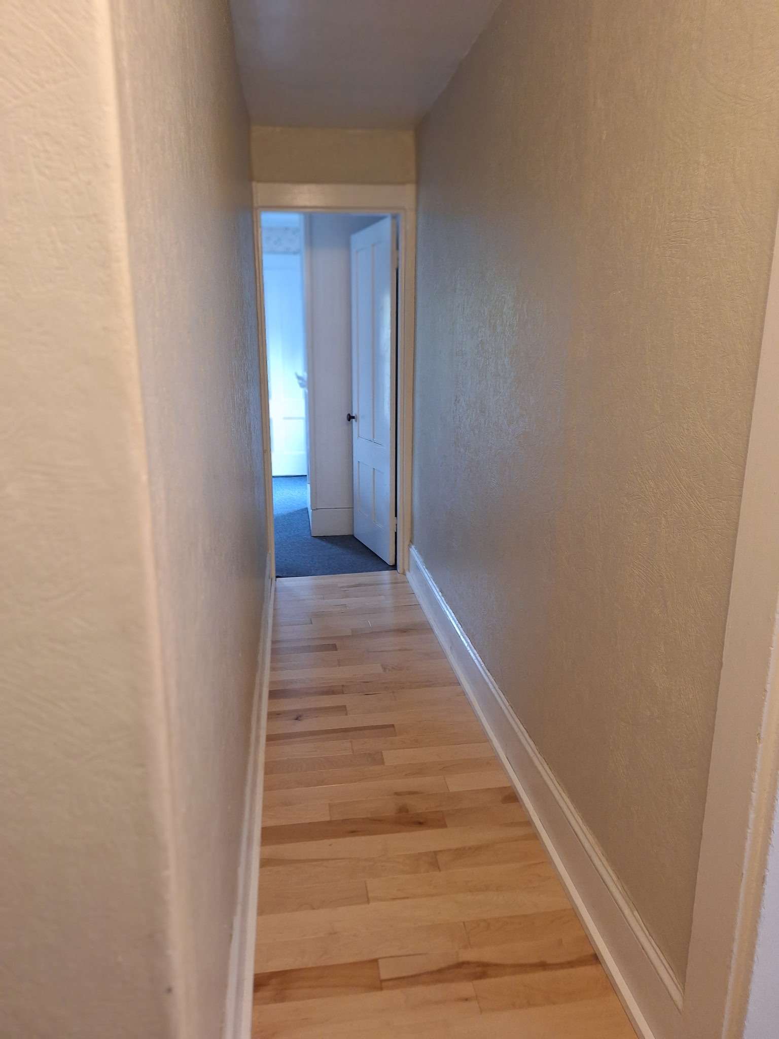 Hallway with hardwood floors connecting rooms in Skowhegan contractor housing