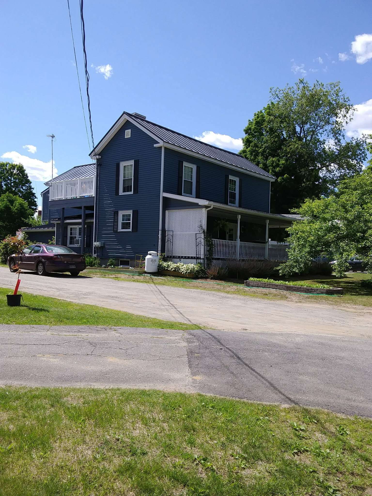 Front view of the blue house with driveway and landscaped yard in Skowhegan - contractor housing